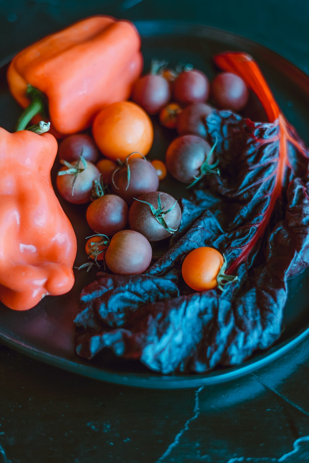 red and blue round fruits on blue ceramic bowl