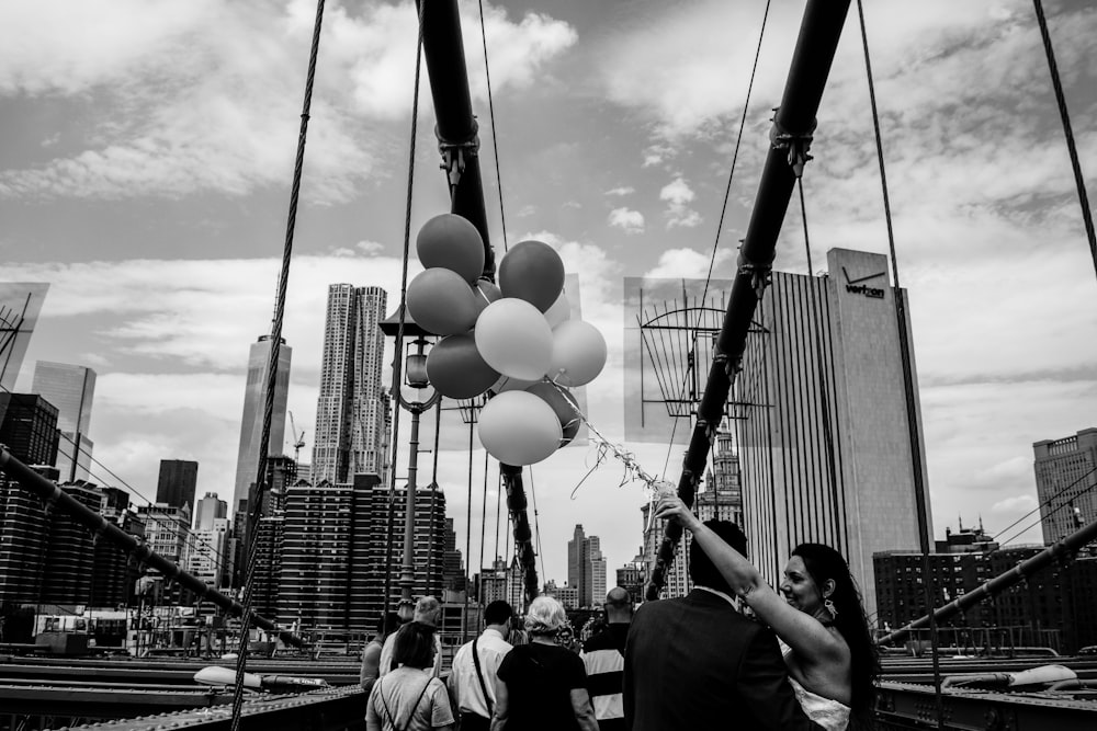 grayscale photo of people walking on street with balloons
