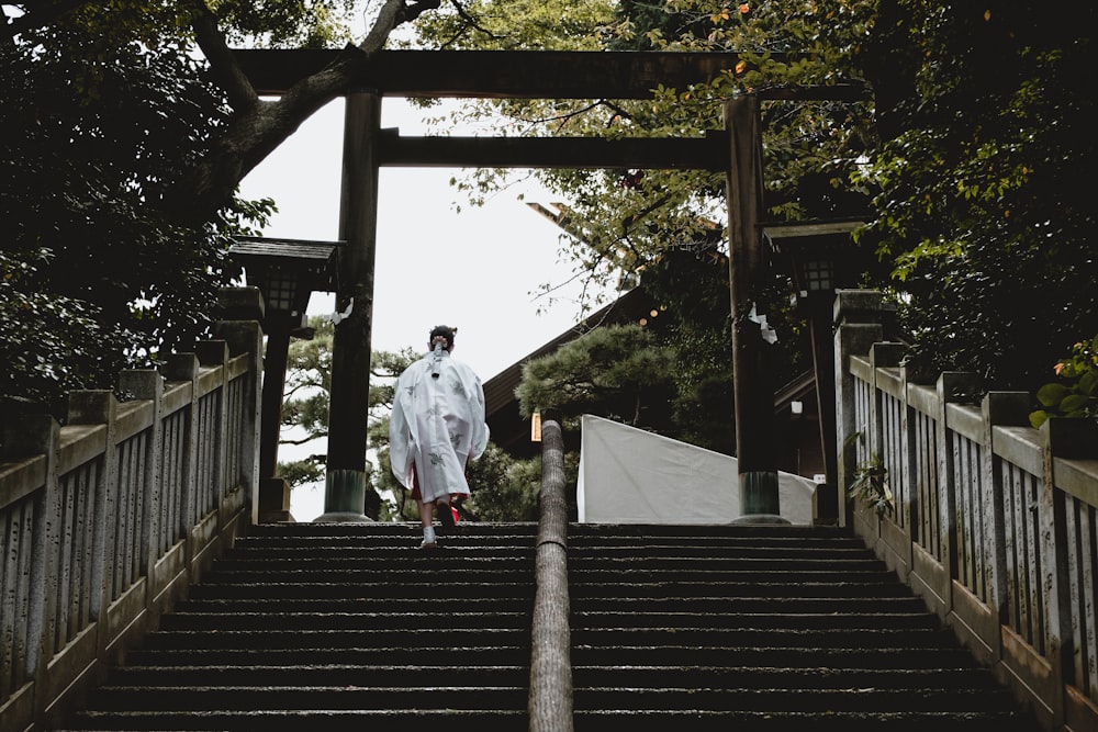 man in white dress shirt walking on brown wooden bridge during daytime