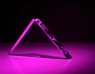 Engineer inspecting a custom prism component under bright workshop lighting.