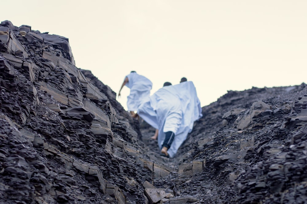 person in white shirt and blue denim jeans walking on rocky mountain during daytime