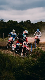 A group of motocross riders racing on a dirt track under a clear sky