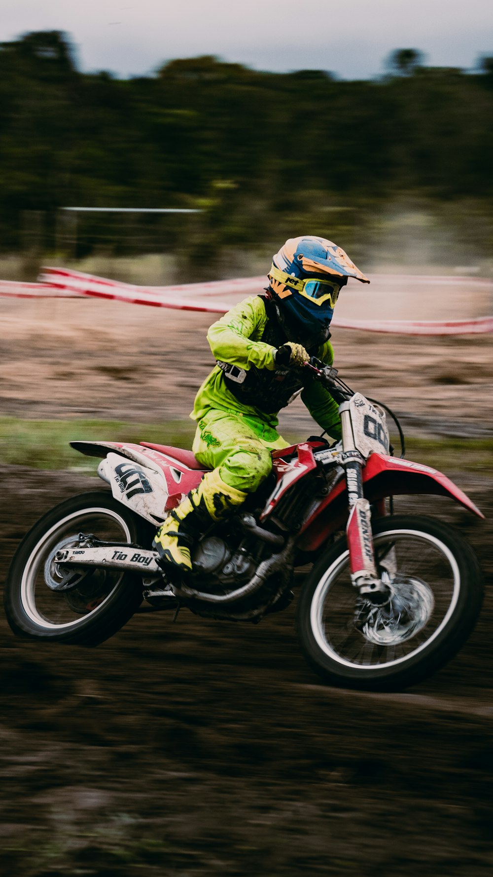man in green and black motorcycle suit riding red and white motocross dirt bike