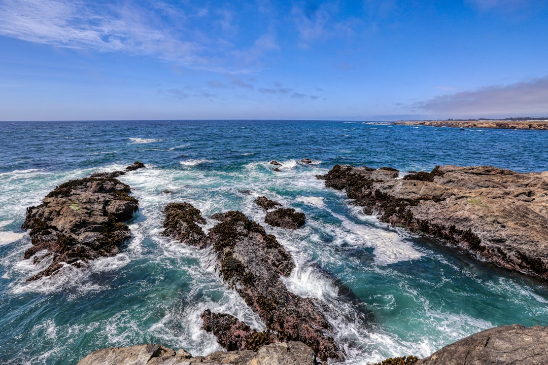 brown rock formation on sea under blue sky during daytime