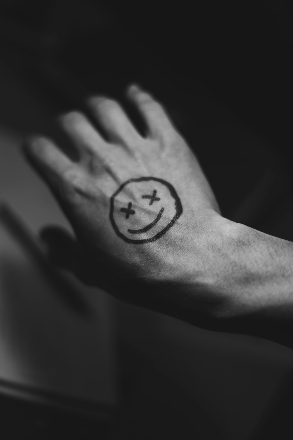 une main avec un tatouage de visage souriant dessus