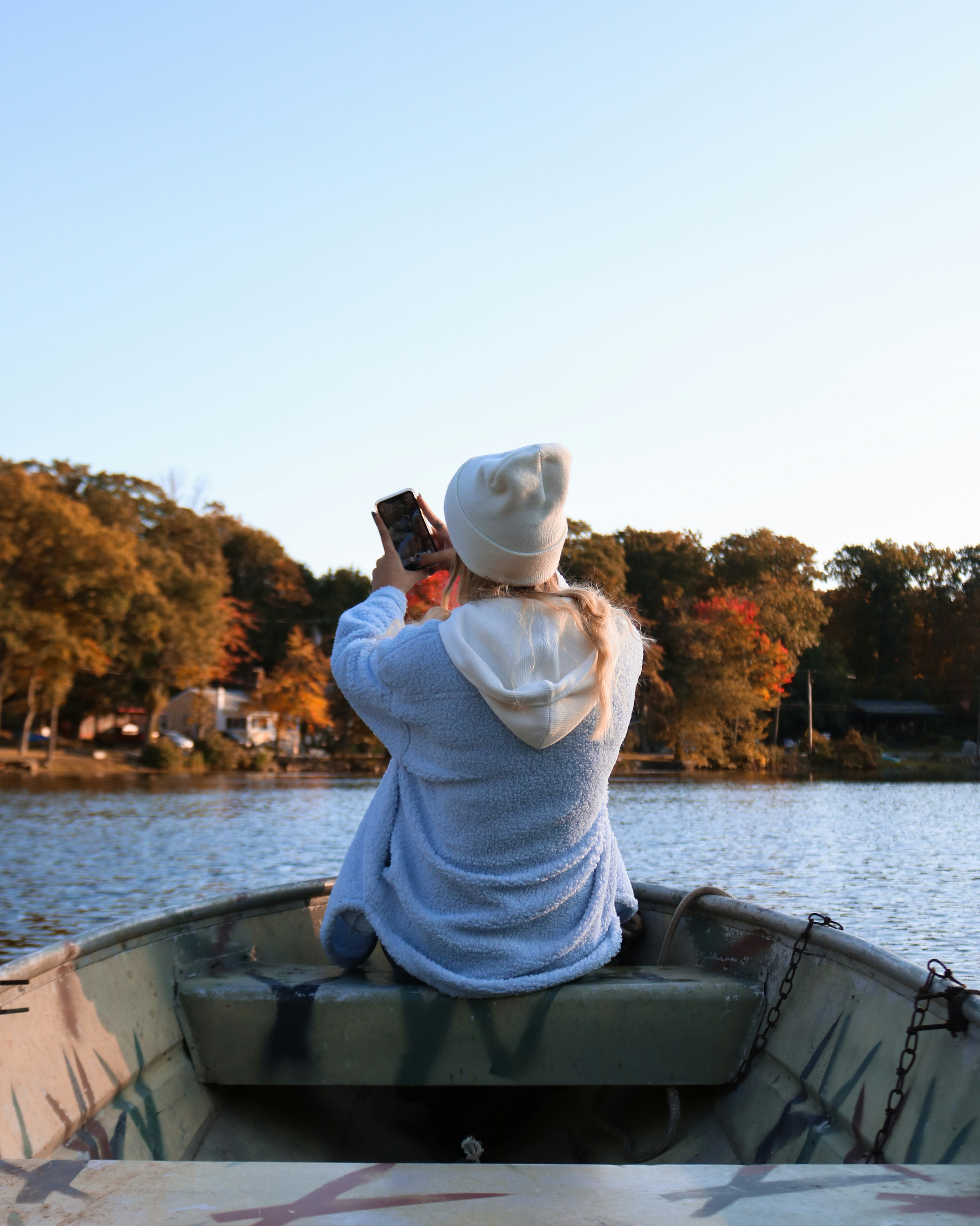 woman in white knit sweater and white knit cap sitting on boat during daytime