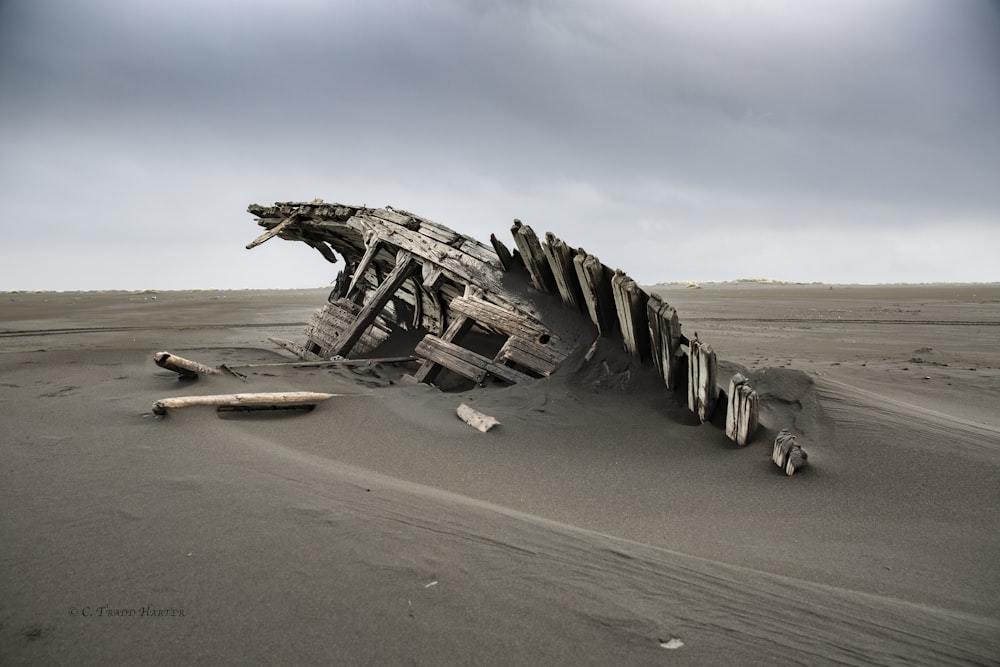 wrecked brown wooden ship on brown sand during daytime