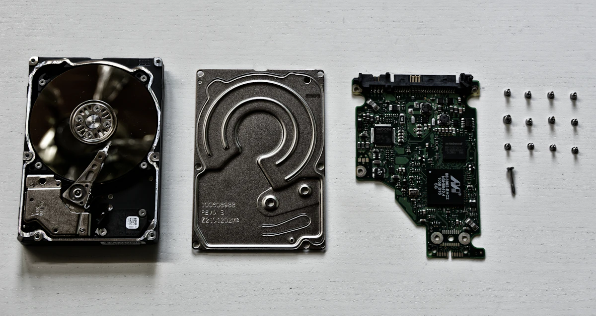 The parts of a disassembled hard disk drive laid out on a white surface
