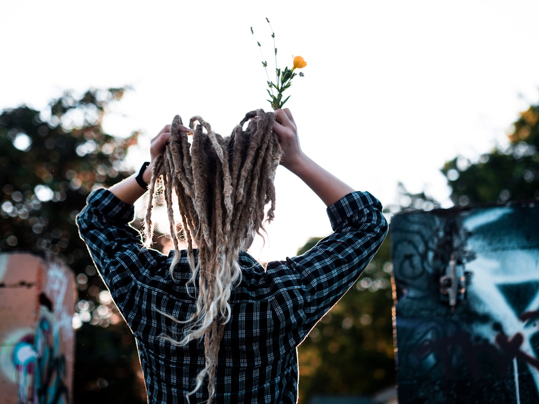 person in blue and white plaid long sleeve shirt holding white flower