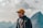 man in blue jacket and yellow cap standing on mountain during daytime