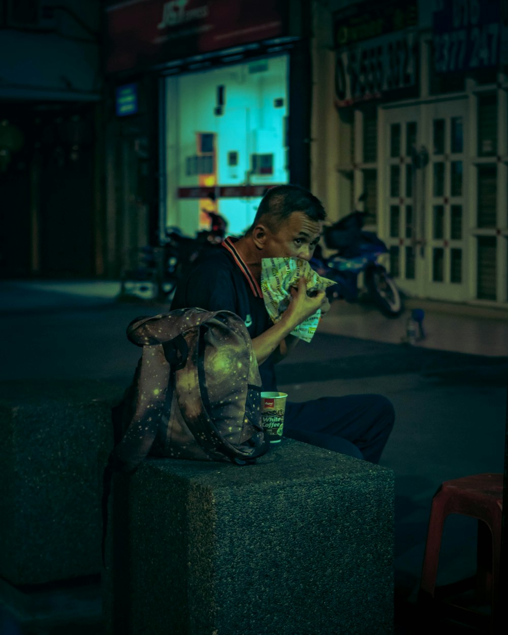 man in black jacket sitting on gray concrete bench