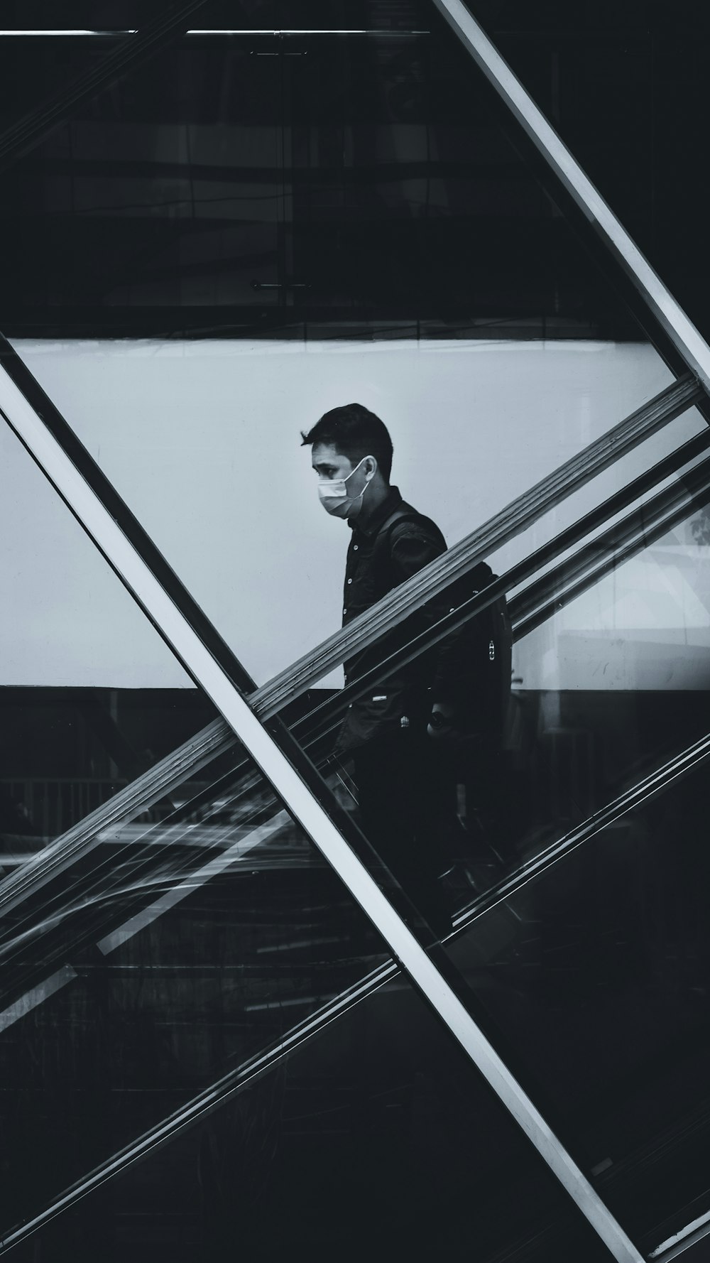 man in black jacket standing beside glass window