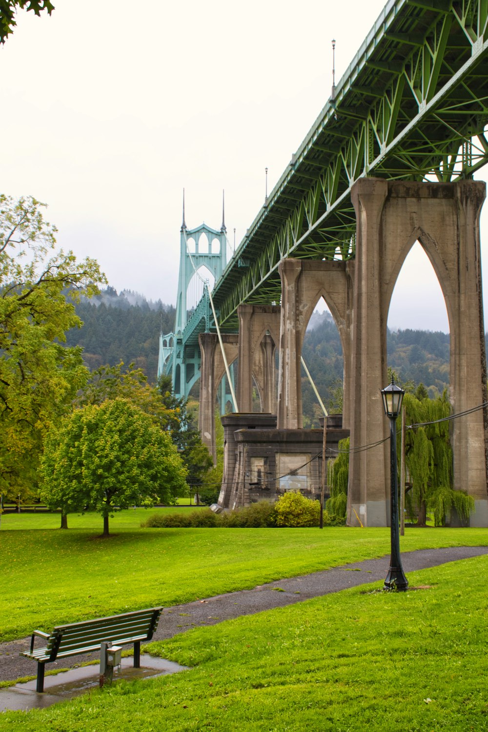 green grass field under gray concrete bridge during daytime