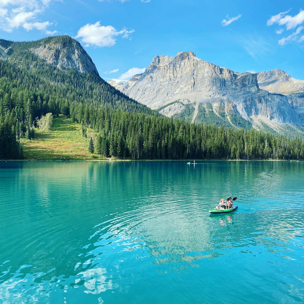 2 people riding on boat on lake near mountain range