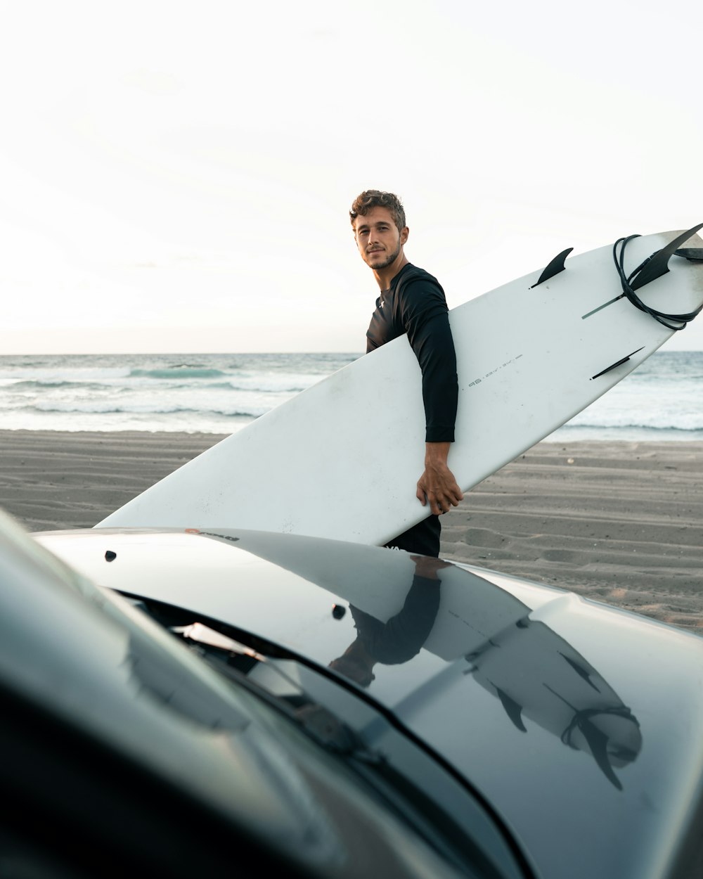 man in black suit holding white surfboard