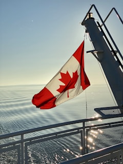 red white and blue flag on gray metal railings near sea during daytime