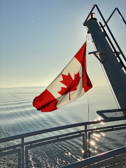 red white and blue flag on gray metal railings near sea during daytime