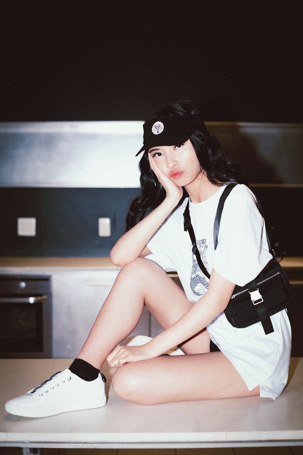 woman in white and black shirt and brown shorts sitting on brown wooden table