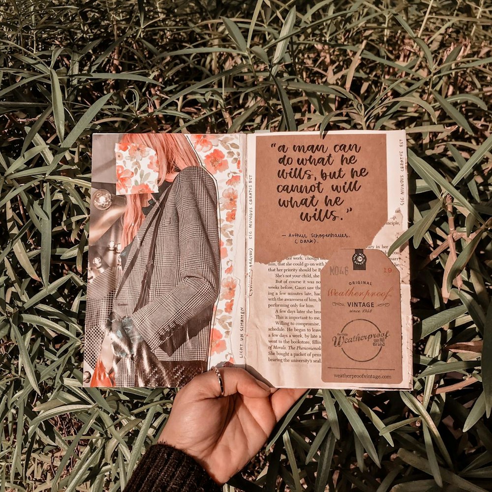 person holding brown and white book