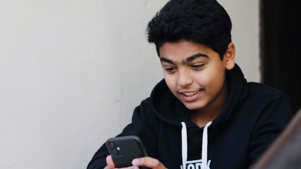 man in black and white hoodie holding black smartphone