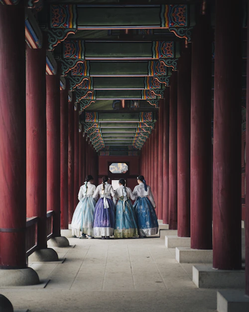 Two people in traditional hanbok in a corridor