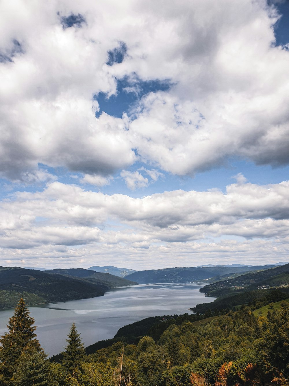 green trees on mountain under white clouds and blue sky during daytime