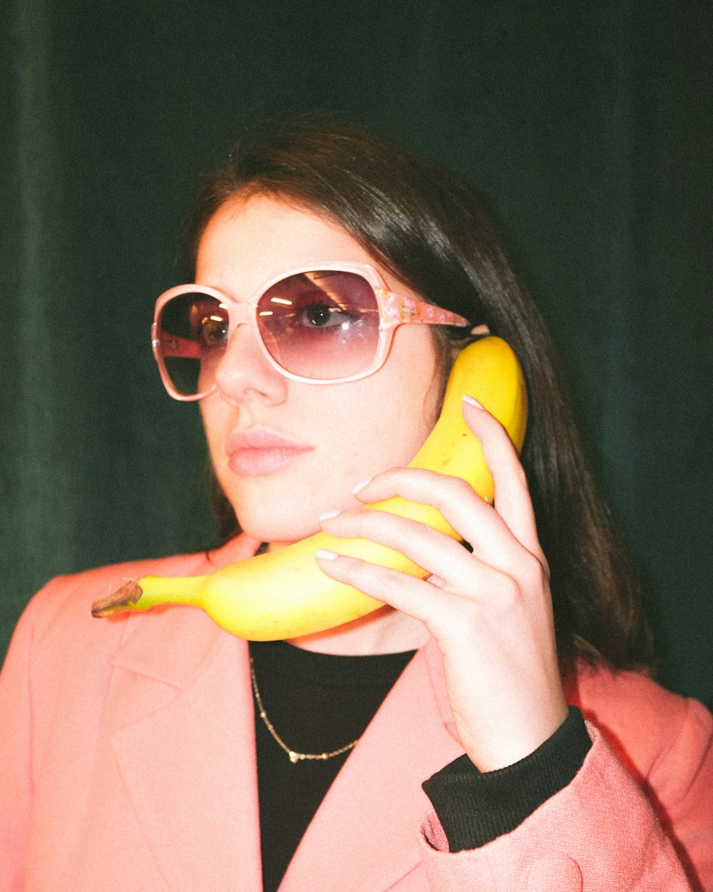 woman in pink blazer holding yellow banana