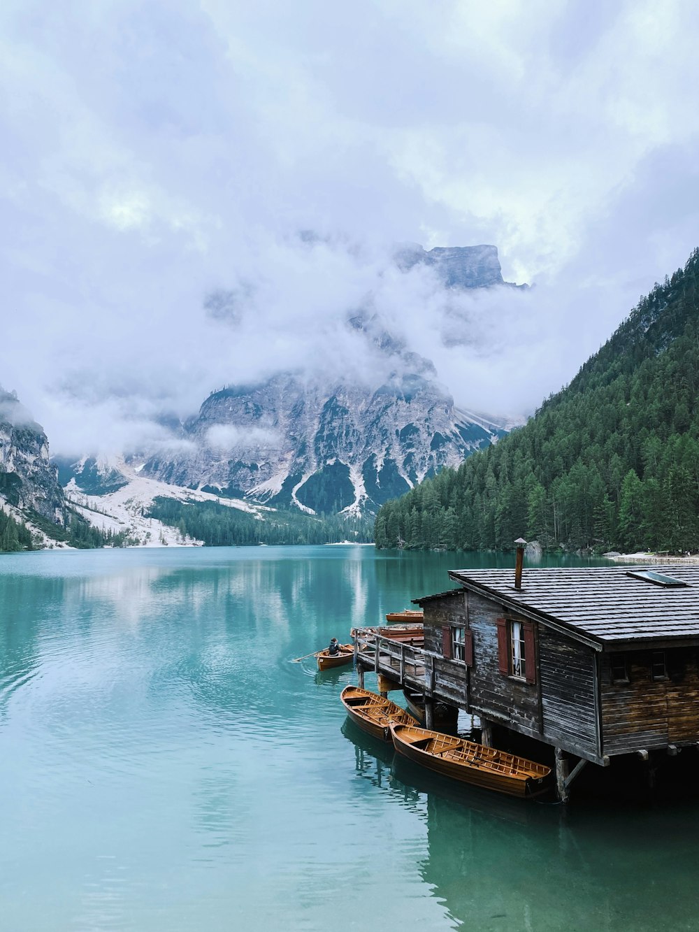 brown wooden house on lake near mountain range