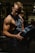 Strong male athlete lifting weights in a modern gym with dark, moody lighting.