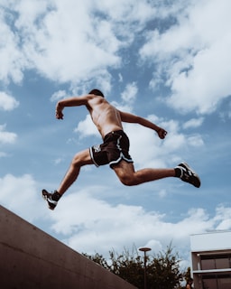 Young athlete leaping between two bars inside the covered parkour training area.