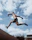 An energetic athlete performing a parkour jump over urban obstacles at the academy.