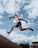 An energetic athlete performing a parkour jump over urban obstacles at the academy.