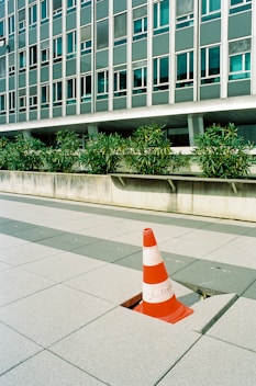 orange and white traffic cone on gray concrete floor