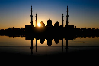 A serene mosque silhouette at sunset with warm golden light reflecting on the minarets.