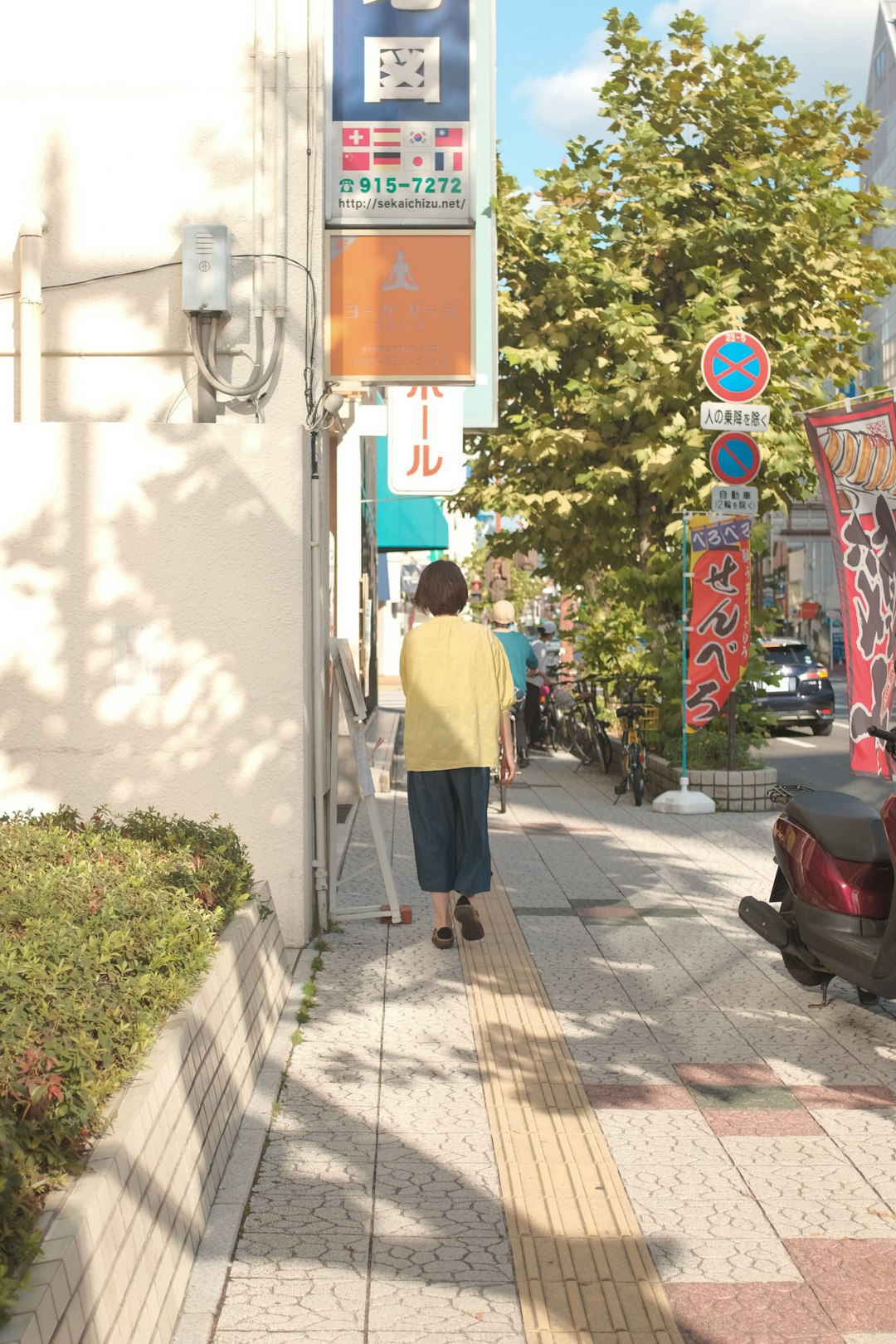 woman in gray shirt walking on sidewalk during daytime