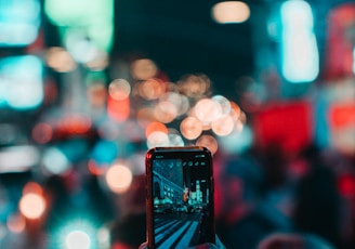 person taking photo of city during night time