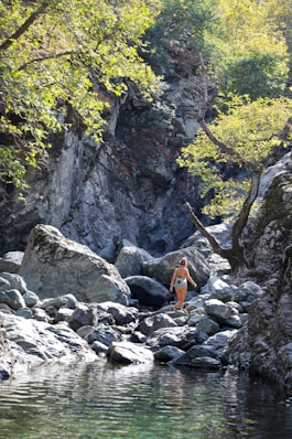 person in orange jacket standing on rocky ground during daytime