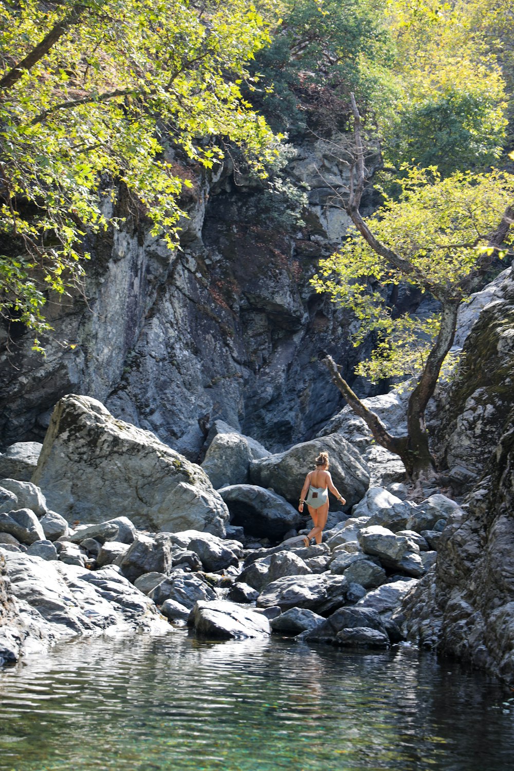 person in orange jacket standing on rocky ground during daytime