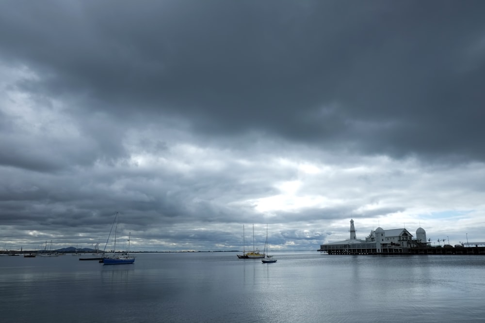 Barco blanco y azul en el mar bajo nubes grises