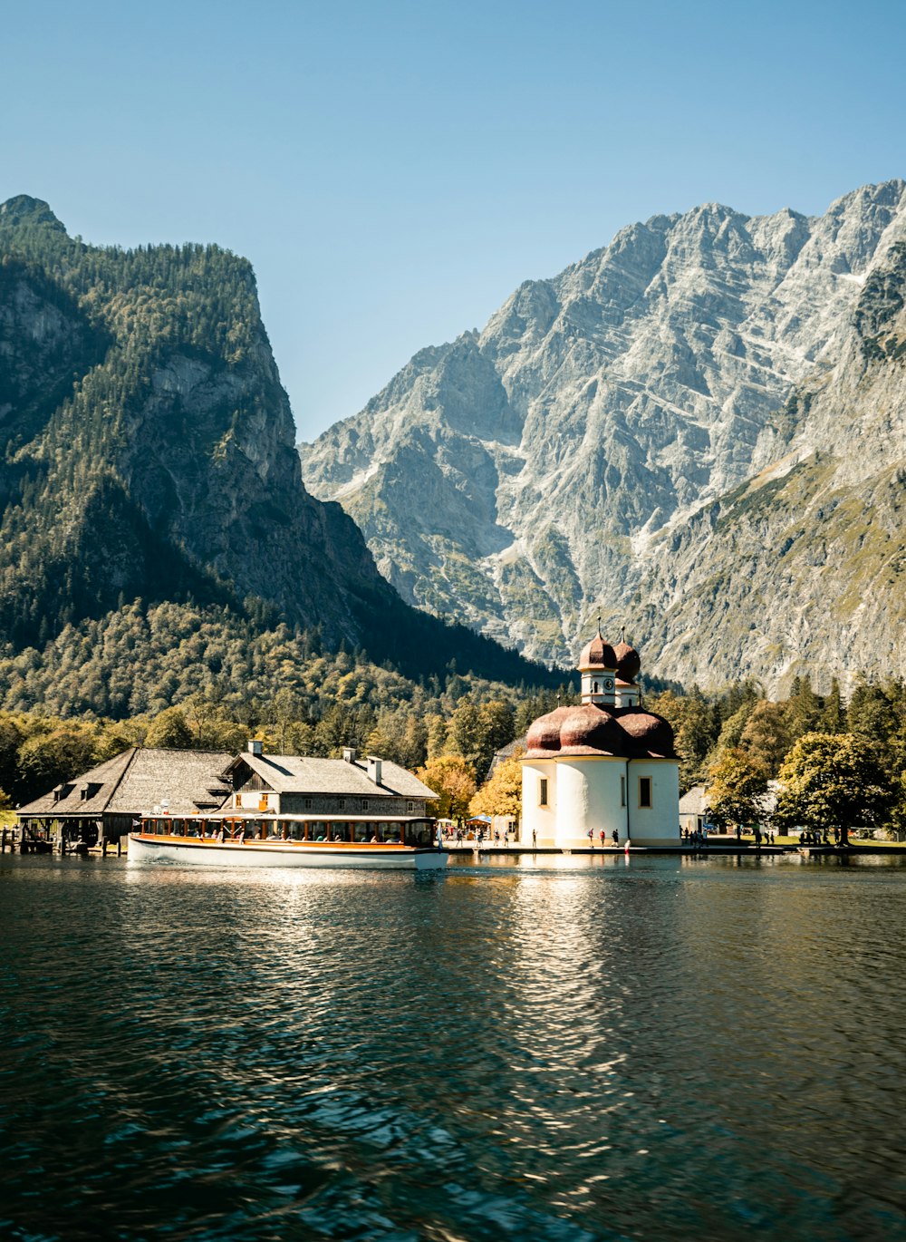 Casa bianca e marrone vicino a specchio d'acqua e montagna