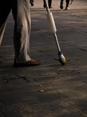 A friendly curb painter holding a brush next to a freshly painted home address and colorful sports team logo on a sunny street.