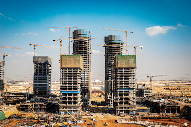 A panoramic view of a bustling construction site in Ras Al Khaimah with cranes and workers actively building a modern structure.