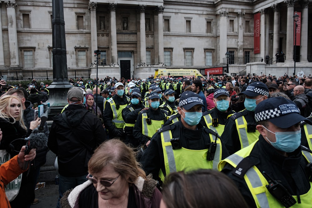 people in green and black jacket standing near building during daytime