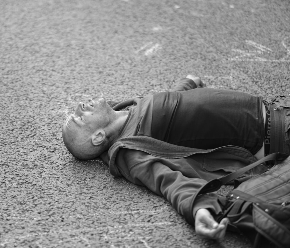 man in black jacket lying on ground