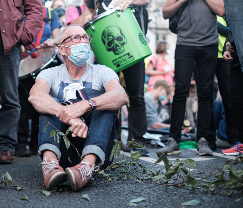 man in black t-shirt and blue denim jeans sitting on ground