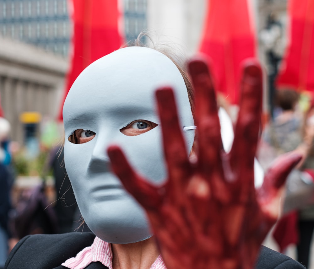 person in white mask with red and white face paint