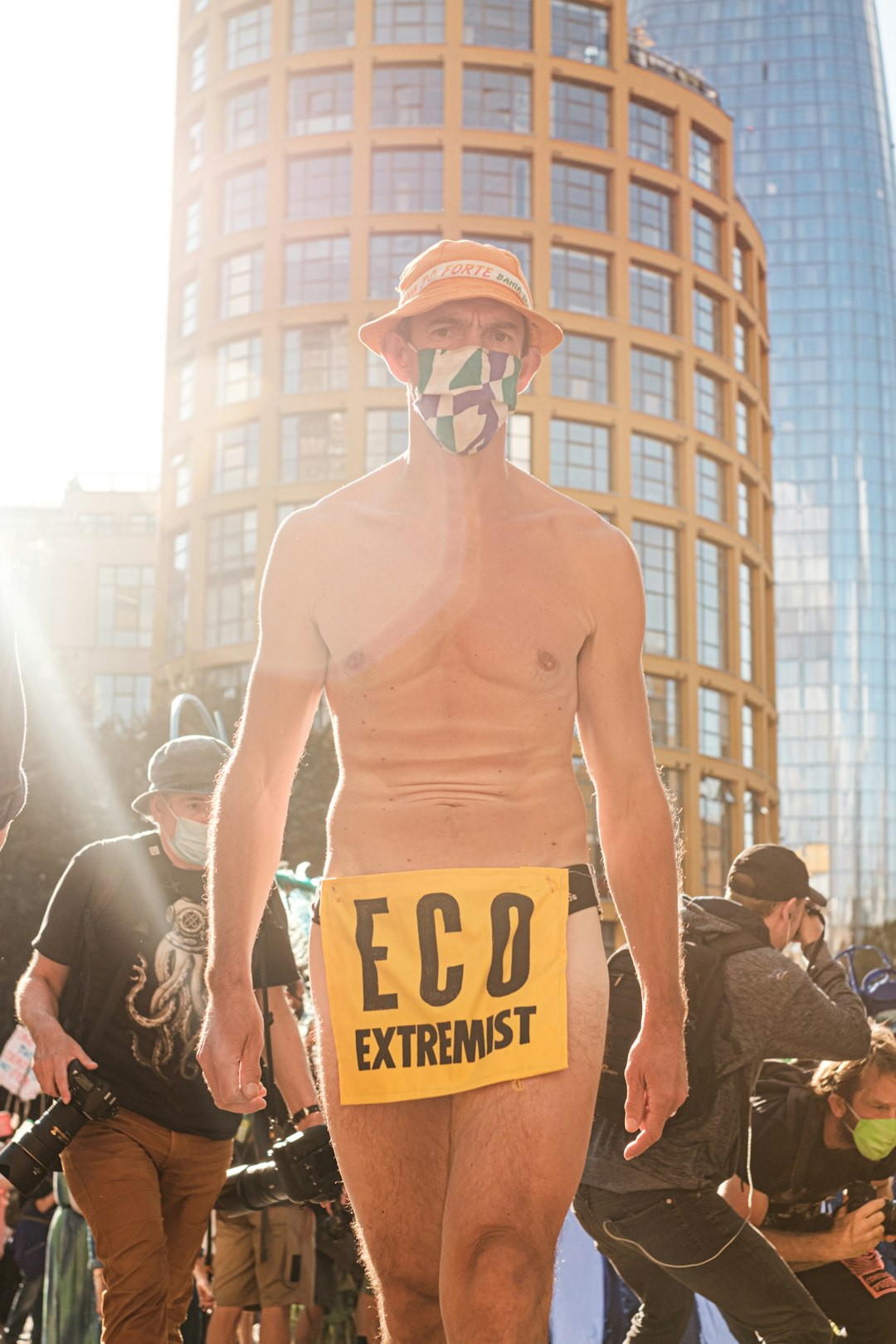 man in yellow tank top wearing white mask standing on street during daytime