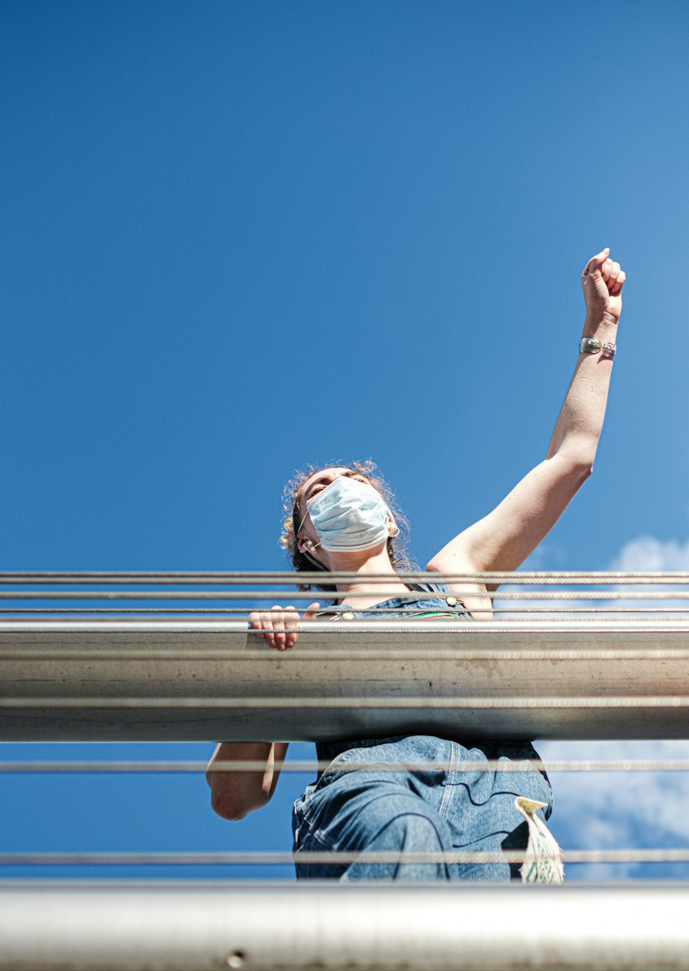 woman in blue denim jacket leaning on brown metal railings during daytime