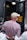 A person wearing a white cap and a checkered shirt is handcuffed and being escorted by police officers. The scene appears to be outside, near a police van with an open door, suggesting an arrest is taking place.