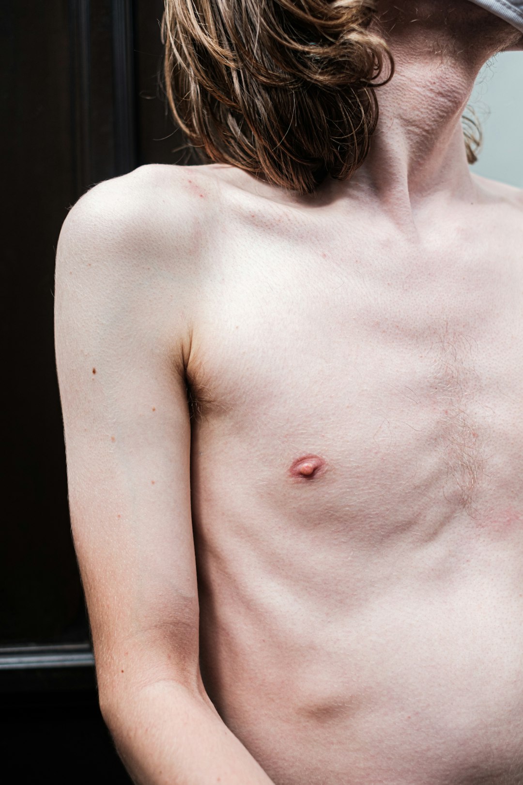 topless woman standing near black wall